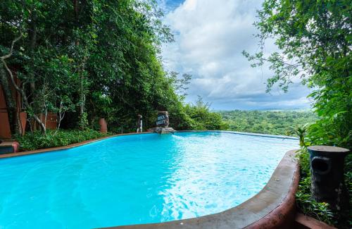 a large blue swimming pool with trees in the background at Treebo Rock Valley in Ponda