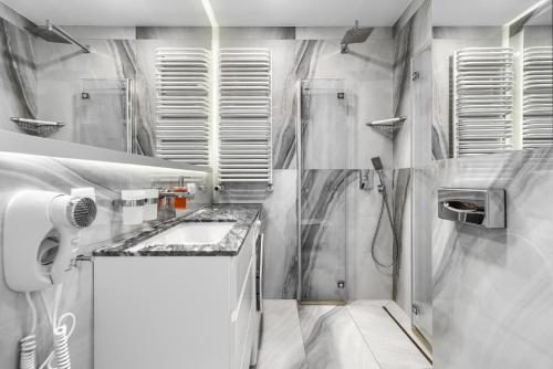 a white bathroom with a sink and a shower at Your Holidays Promenada Gwiazd 14 in Międzyzdroje
