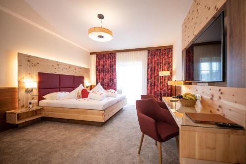 a hotel room with a large bed and a desk at Thermenhotel PuchasPLUS Stegersbach in Stegersbach