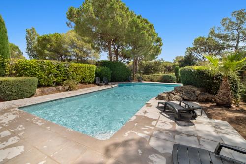 - une piscine dans une cour avec des chaises et des arbres dans l'établissement Le 11 - Appt climatisé avec piscine partagée, à Saint-Raphaël