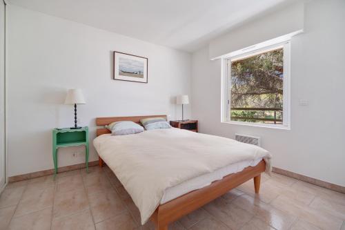 Un dormitorio blanco con una cama grande y una ventana en Le 11 - Appt climatisé avec piscine partagée, en Saint-Raphaël