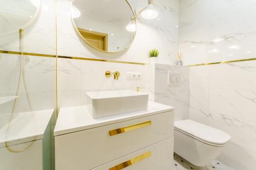 uma casa de banho branca com um lavatório e um espelho em Mia Mare Premium Apartment by Perłowa Przystań Rent em Kolobrzeg