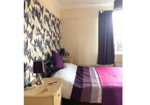 a bedroom with a bed and a table and a window at Scardroy Falkirk - Central 3 Bedroom Apartment with Parking, WiFi, Smart TVs in Falkirk