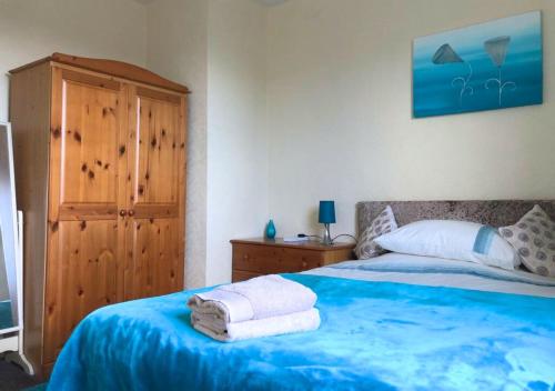 a bedroom with a blue bed with towels on it at Scardroy Falkirk - 3 Bedroom Apartment in Falkirk