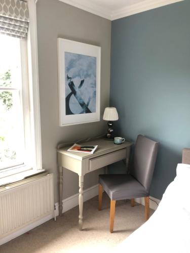 a desk in a bedroom with a chair and a lamp at Balcarres, Rodborough Avenue in Stroud