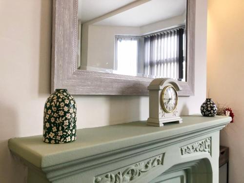 a mirror above a fireplace with a clock on it at Home 2 Home Living in Clayton le Moors