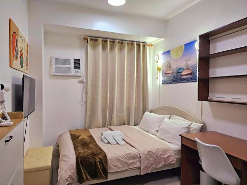 a small bedroom with a bed and a desk at Acellyne Suites at Green 2 Residences with Netflix! in Dasmariñas