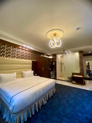 a bedroom with a large white bed and a chandelier at Aral Hotel Apartments in Tabuk