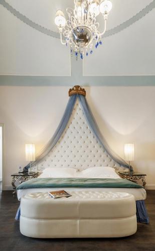 a bedroom with a large bed with a chandelier at Relais Antica Badia - San Maurizio 1619 in Ragusa