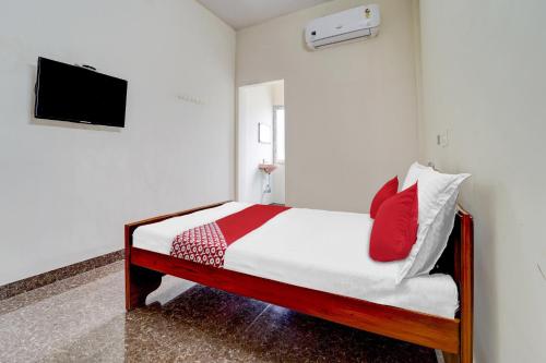 a bedroom with a bed and a tv on a wall at OYO Flagship V A S Lodge in Punjai Puliyampatti
