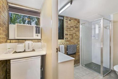 a bathroom with a shower and a sink and a toilet at Golden Beach Motor Inn, Caloundra in Caloundra