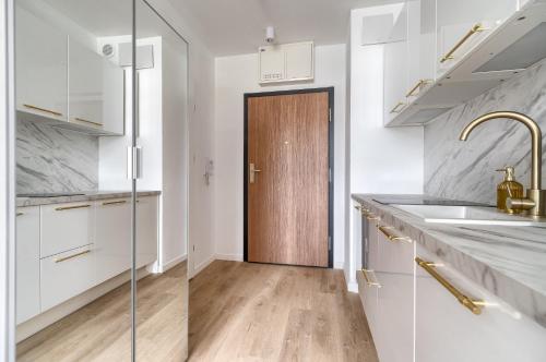 a kitchen with white cabinets and a wooden door at Your Holidays Bel Mare Aqua in Międzyzdroje