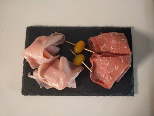 a plate with meat and grapes on a table at LA TANA DELLA VOLPETTA - Bed & Breakfast in Stella