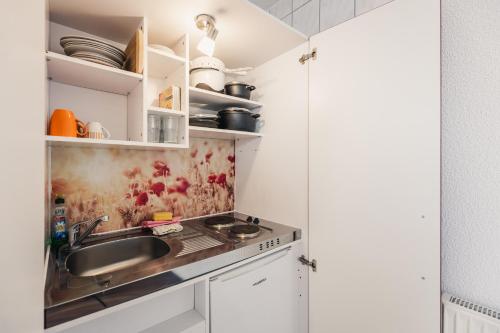 a kitchen with a sink and white cabinets at Hotel Seeblick in Barhöft