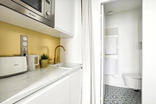 eine Küche mit einer Spüle und einer Mikrowelle in der Unterkunft PL1 - Stylish architect studio near Le Marais in Paris