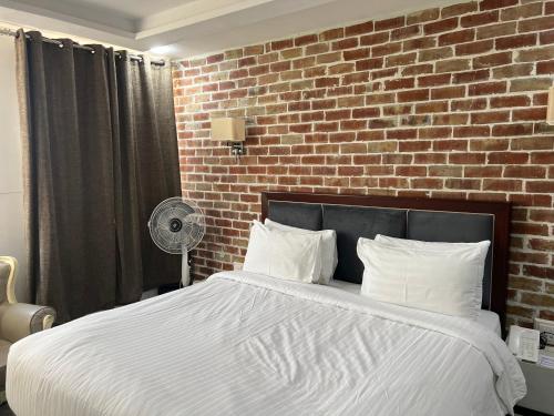 a bedroom with a large bed with a brick wall at Hotel Hayatt Sukkur in Kalar Goth