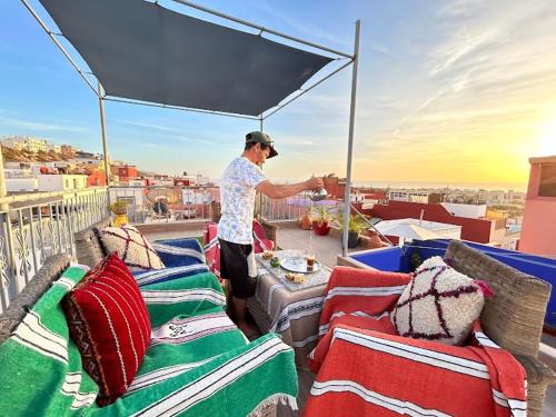 a man standing on top of a balcony with pillows at TRAVEL SURF NATURE in Tamraght Ouzdar