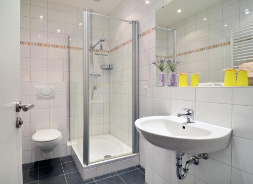 een badkamer met een douche, een wastafel en een toilet bij Hotel am Bahnhof in Aken