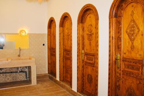 four wooden doors in a bathroom with a sink at TRAVEL SURF NATURE in Tamraght Ouzdar