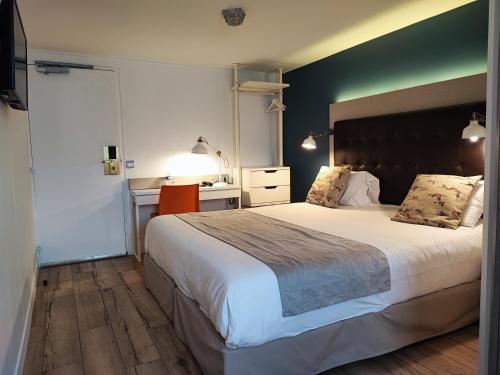 a bedroom with a large bed and a desk at Kyriad Argenteuil in Argenteuil