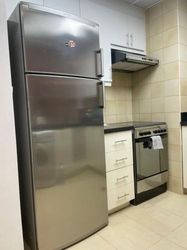 a stainless steel refrigerator in a kitchen next to a stove at Sunset Oasis: Beachfront Studio in Dubai