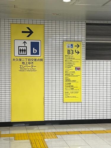 two signs on the wall of a subway station at City Hotel Dolphin in Tokyo