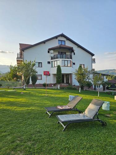 two lounge chairs on the grass in front of a house at Pensiunea Tabacaru in Peştera