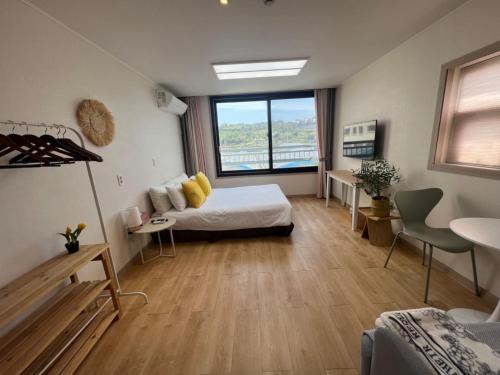 um quarto com uma cama e uma grande janela em Living in Jeju Island em Jeju