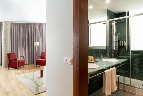 een badkamer met 2 wastafels en een rode stoel bij Parador de Soria in Soria