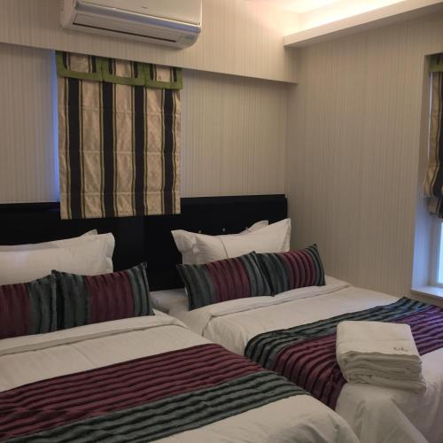 a hotel room with two beds with striped pillows at Seasons Hotel - Causeway Bay in Hong Kong