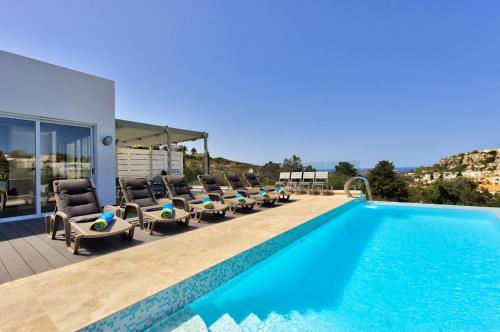 eine Villa mit einem Pool und Liegestühlen in der Unterkunft Villa Ghea - Indoor Jacuzzi Pool, Sauna and Games Room in Mellieħa