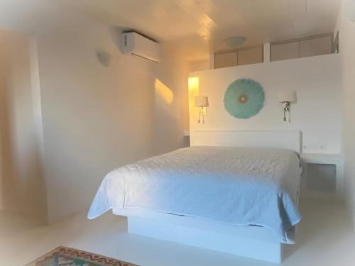 a white bedroom with a white bed with a blue light at Rustic Stone House in the Heart of Folegandros in Áno Meriá
