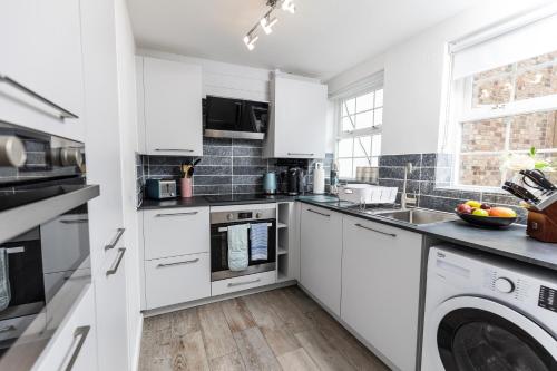 a kitchen with white cabinets and a washer and dryer at 6 Elizabeth House - By Luxury Apartments in Cheltenham
