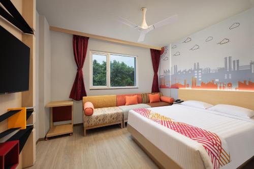 a bedroom with a bed and a couch and a tv at Ginger Noida 63 in Noida