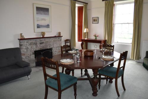 a dining room with a table and chairs and a fireplace at Craignuisq Farmhouse in Pitlochry