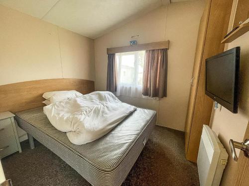 a small room with a bed and a television at Superb Caravan With Free Wifi At Seawick Holiday Park Ref 27022s in Clacton-on-Sea