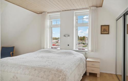 a white bedroom with a bed and two windows at Beautiful Home In Nysted With House Sea View in Nysted