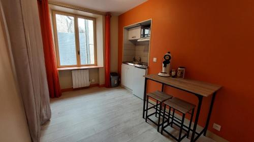 - une cuisine aux murs orange avec une table et des chaises dans l'établissement Le Madison 1, à Châteauroux