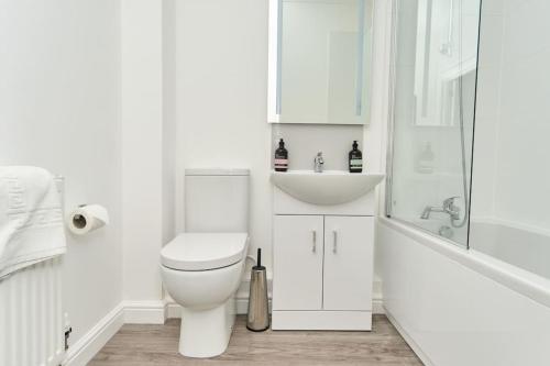 a white bathroom with a toilet and a sink at The Penthouse In Bonchurch Village by Greenstay Serviced Accommodation - Stunning 3 Bed Apt With Parking & Sea Views - The Perfect Choice For Families, Small Groups & Business Travellers in Ventnor