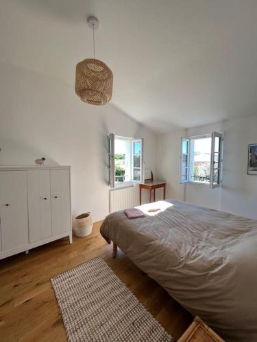 une chambre blanche avec un grand lit et deux fenêtres dans l'établissement Grande maison proche de la plage, à La Couarde-sur-Mer