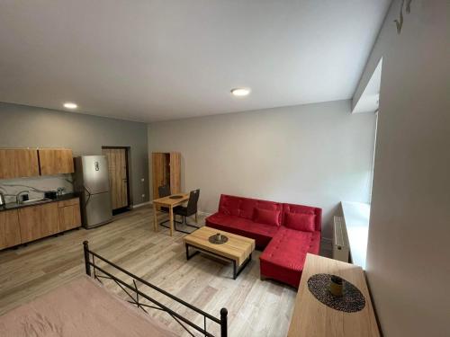 a living room with a red couch and a kitchen at Apartamentai in Raseiniai