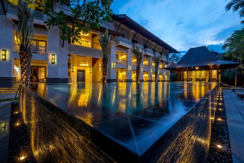 an empty pool in front of a building at night at Puri Santrian Beach Resort And Spa in Sanur