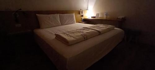 a bed in a hotel room with a white blanket on it at Kanalung Yurakucho House in Taimali