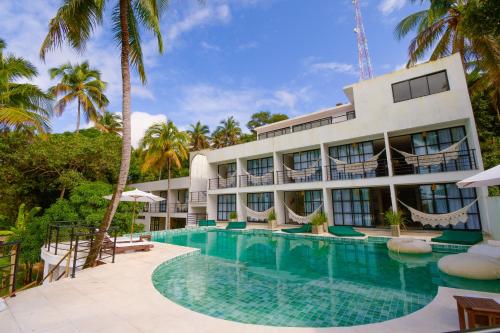 una vista exterior de un hotel con piscina en Milie Lounge Pousada, en Japaratinga