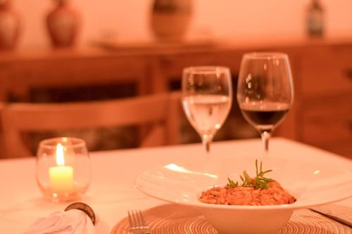 a table with a plate of food and two wine glasses at Milie Lounge Pousada in Japaratinga