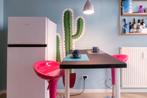 eine Küche mit einem Tisch und 2 rosa Hockern in der Unterkunft Casa Del Cactus - Bergamo City - by Host4U in Bergamo