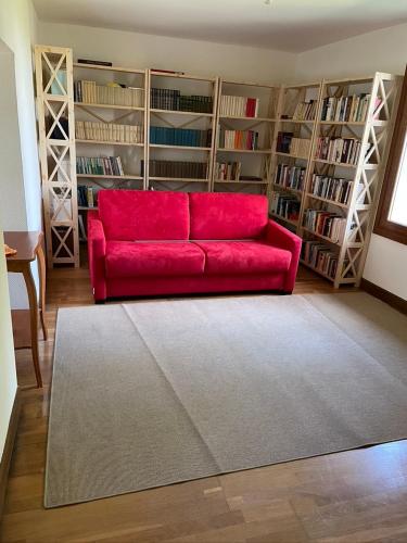 - un canapé rouge dans le salon doté d'étagères dans l'établissement Bienvenue à Champlay, à Champlay