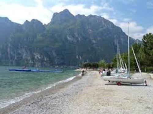 een strand met boten erop met een berg bij CASA degli OLIVI GARDA LAKE in Riva del Garda