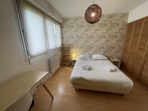 a bedroom with a bed and a desk and a window at Saturne YourHostHelper in Caen