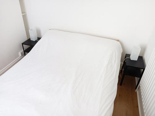 a white bed in a room with two night stands at Maison Blanc in Nottingham